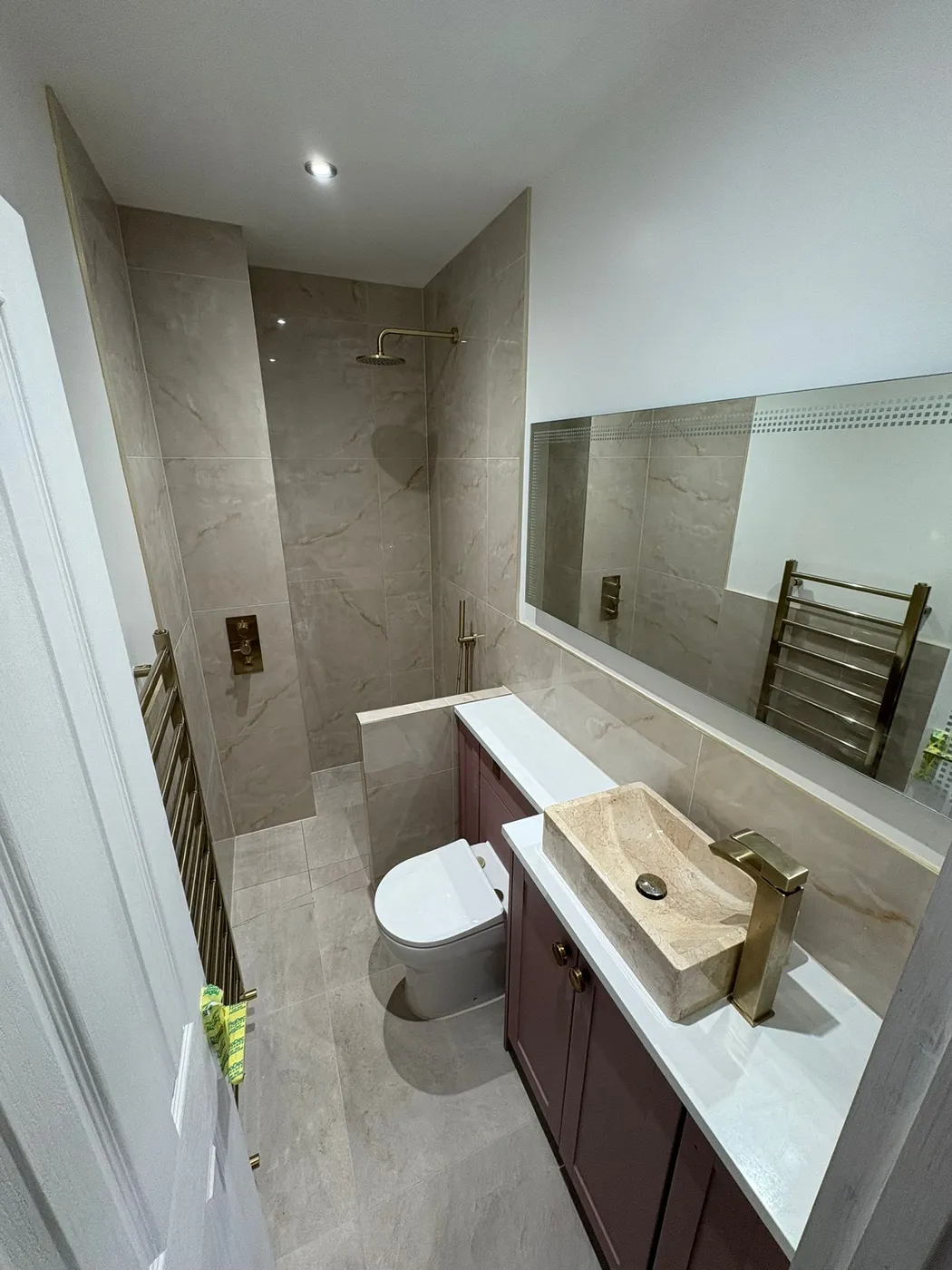 Full bathroom renovation with stone vessel basin, brass fittings, plum vanity unit, large mirror and walk-in marble-effect shower.