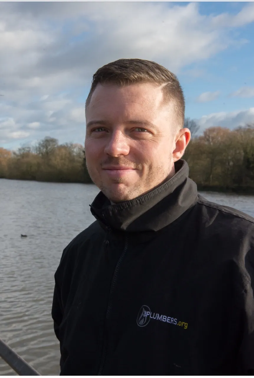 Portrait of the company owner in ThePlumbers.org branded workwear by the River Thames in West London.
