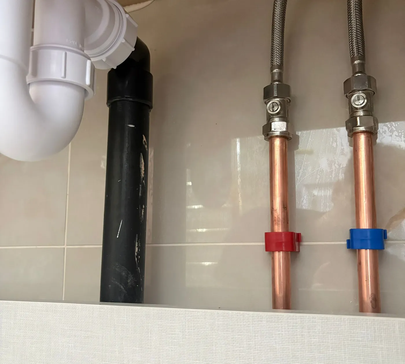 First-fix plumbing with copper hot and cold pipework, flexible connectors and solvent-weld waste pipe neatly clipped.