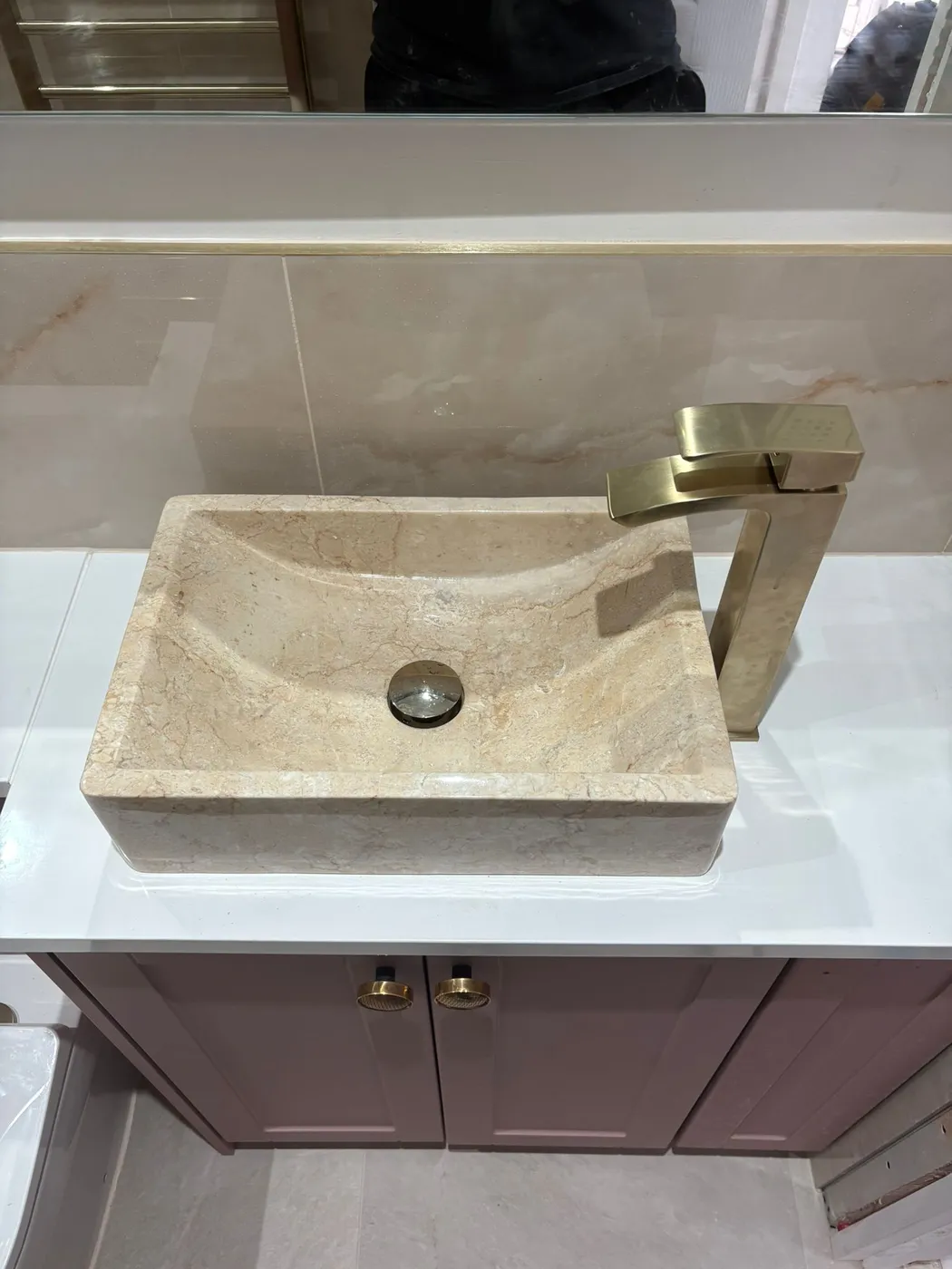 Natural stone countertop basin with brushed brass mono tap fitted on a plum shaker vanity with white worktop.