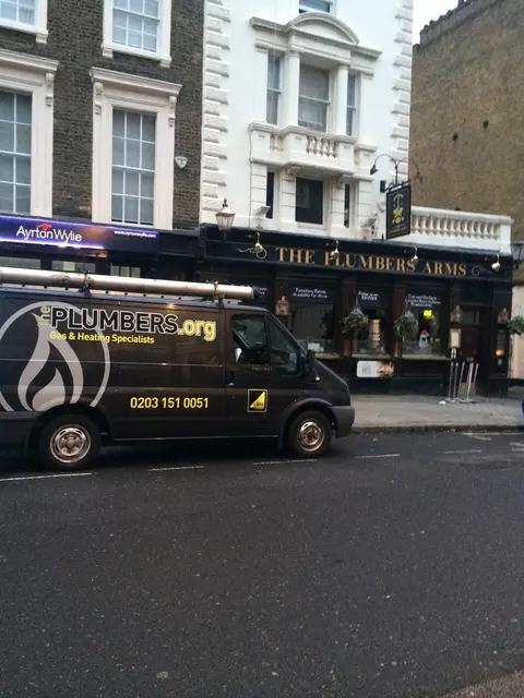 ThePlumbers.org branded black Transit van with Gas Safe logo parked outside The Plumbers Arms pub in London.
